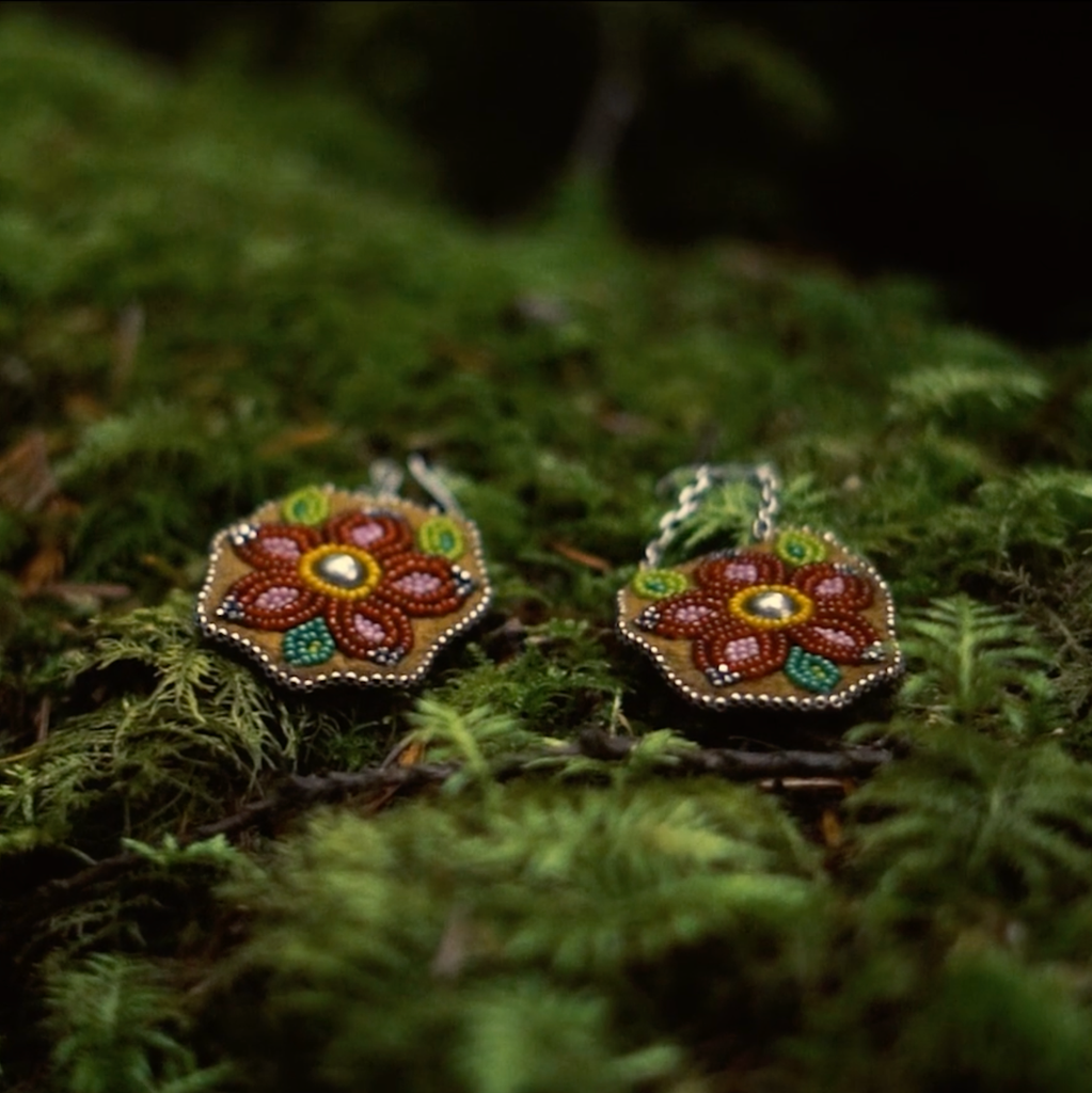 Red Beaded earrings lay on green moss